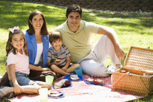 Hispanic family picnicking in the park and smiling at viewer.